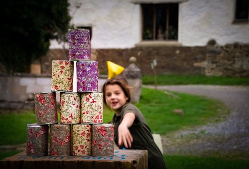 An image of a young girl knocking down a stack of cans